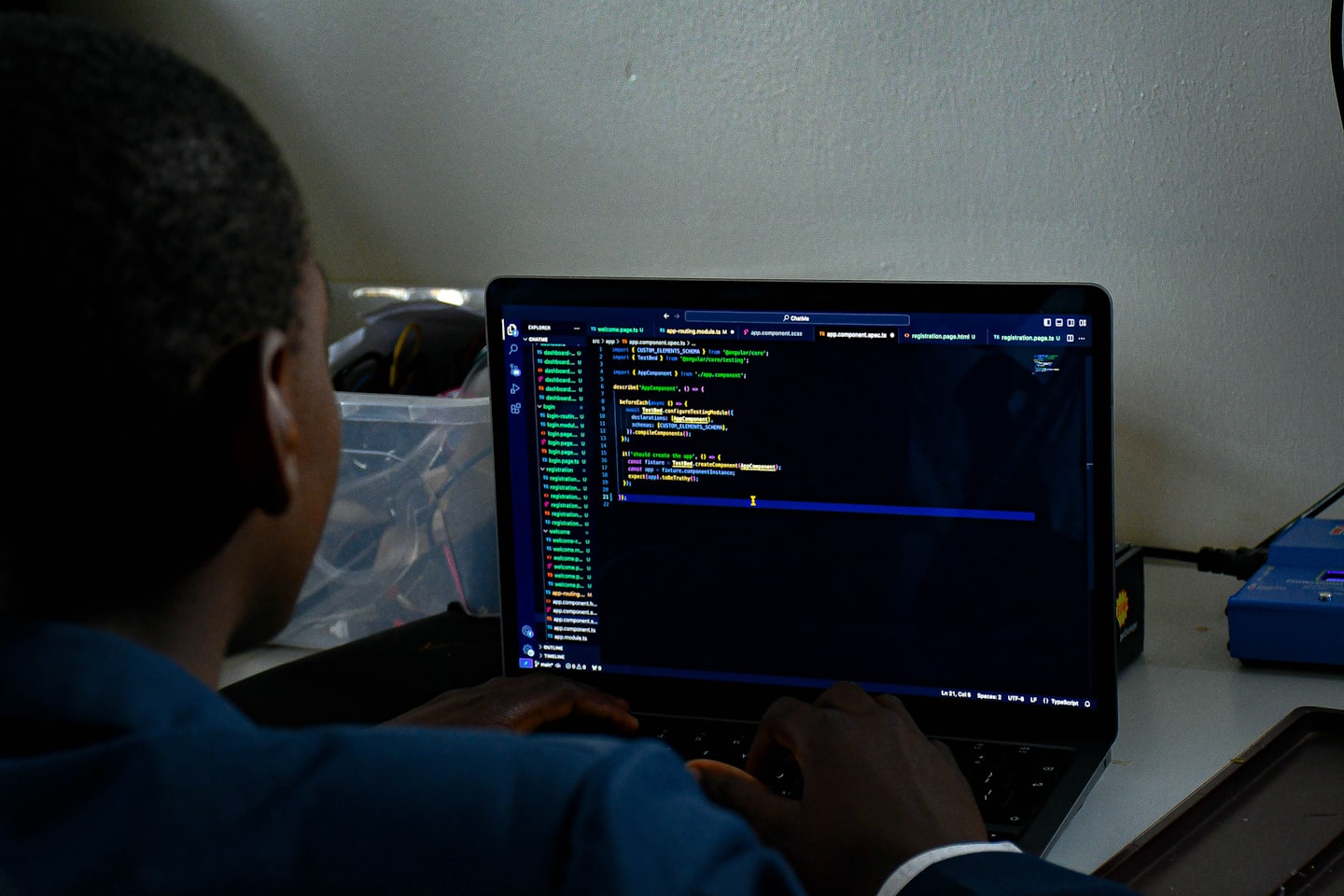 Person typing code on a laptop in a workspace.