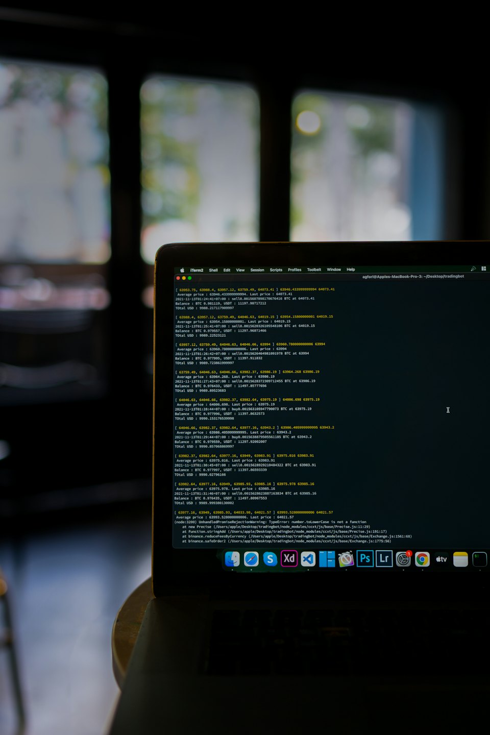 Laptop screen displays cryptocurrency trading code and data charts.